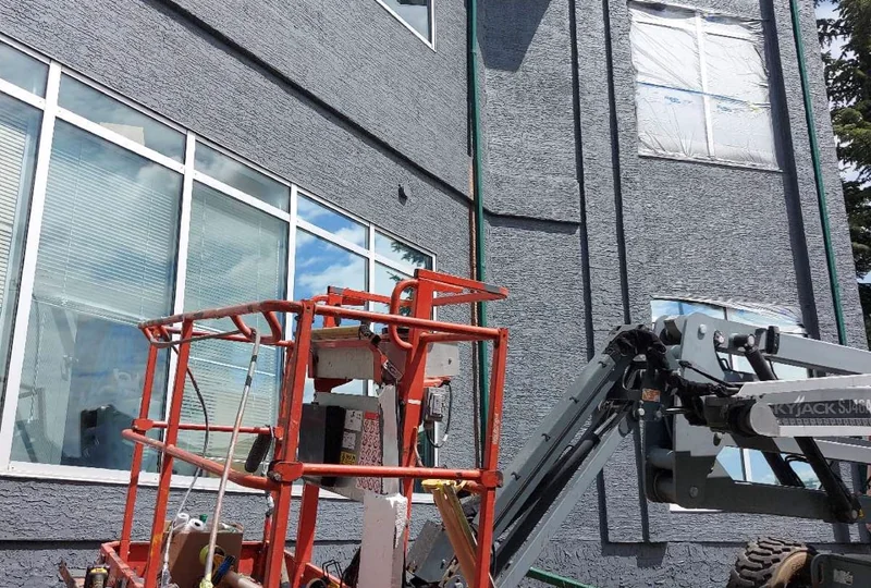 Exterior stucco coating in progress from a boom lift in Calgary
